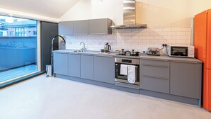 Una cocina moderna con armarios grises, horno empotrado, microondas y tostadora.