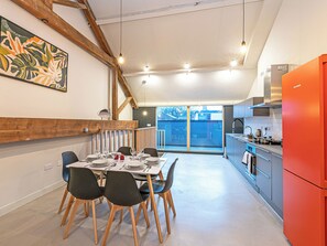A modern kitchen with a bright red refrigerator, wooden beams, and a dining area with a table set for four. - Apartment 16-UK42640 (Preston)