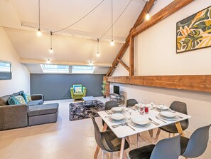 A dining area with a table set for six, a green armchair, and a grey sofa. - Apartment 16-UK42640 (Preston)