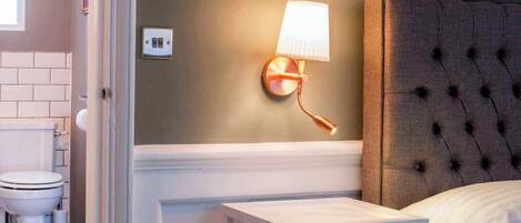 A bathroom with a toilet, a white sink, a mirror, and a wall-mounted light fixture.