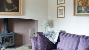 A living room with a fireplace, a sofa, and three framed artworks on the wall. - 2 bedroom accommodation in Near Cheltenham (Near Cheltenham)