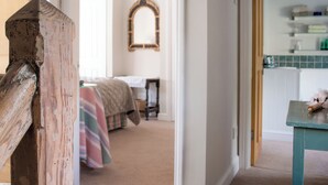 A room with a bed, a table, and a mirror on the wall. - 2 bedroom accommodation in Near Cheltenham (Near Cheltenham)