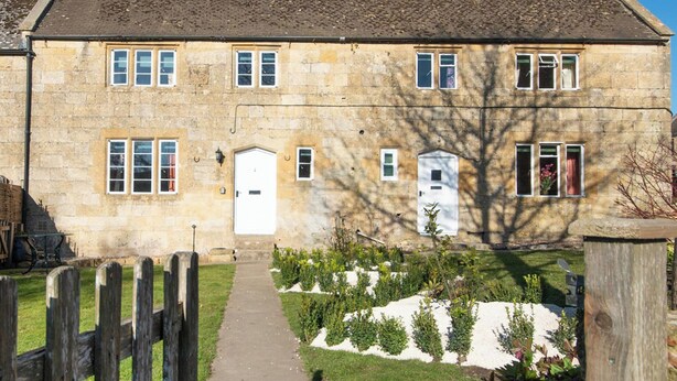 A stone building with a central door, multiple windows, and a garden with a gravel path. - 2 bedroom accommodation in Near Cheltenham (Near Cheltenham)