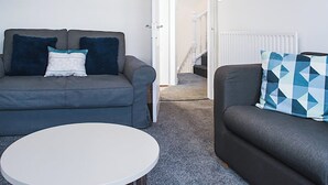 A living room with a grey sofa, a white coffee table, and a blue and white patterned cushion. - Shirehampton Apartment (Shirehampton)