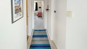 A hallway with a striped carpet, a framed picture on the wall, and a red chair in the background. - 2 bedroom accommodation in Bristol (Bristol)