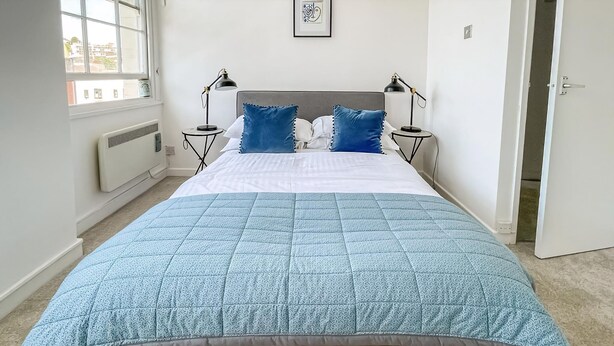 A bedroom with a bed, bedside tables, a window, and a door. - 2 bedroom accommodation in Bristol (Bristol)