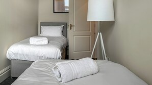 Ein Hotelzimmer mit zwei Betten, einer weißen Lampe und einer Tür.