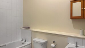 Ein Badezimmer mit Badewanne, Toilette, Waschbecken und einem Spiegel darüber.
