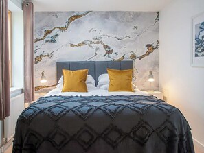 A bedroom with a marble-patterned wall, a dark headboard, and two bedside lamps.