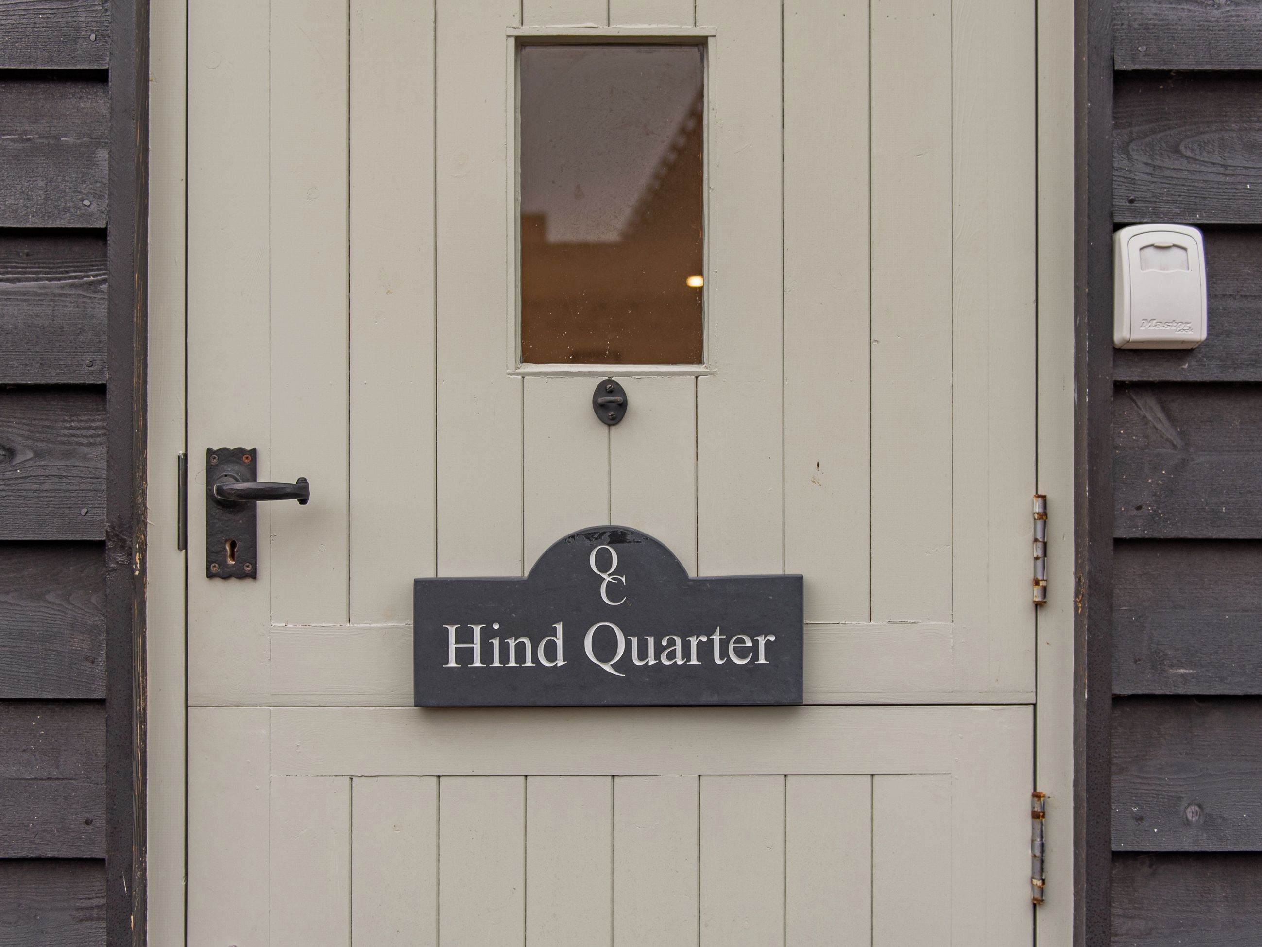 A door with a sign reading "Hind Quarter" and a small window above it.