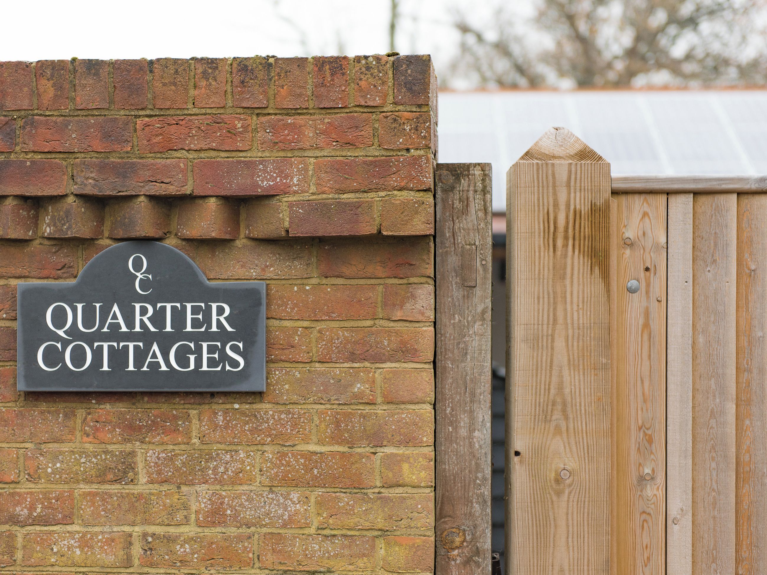A brick wall with a sign that reads "Quarter Cottages."