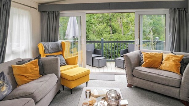 Ein modernes Wohnzimmer mit zwei Sofas, einem gelben Sessel und einem Couchtisch mit Snacks und einem Glas.