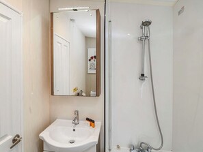 A bathroom with a white sink, a mirror, and a shower. - Mulberry Lodge - UK51192 (Morpeth)