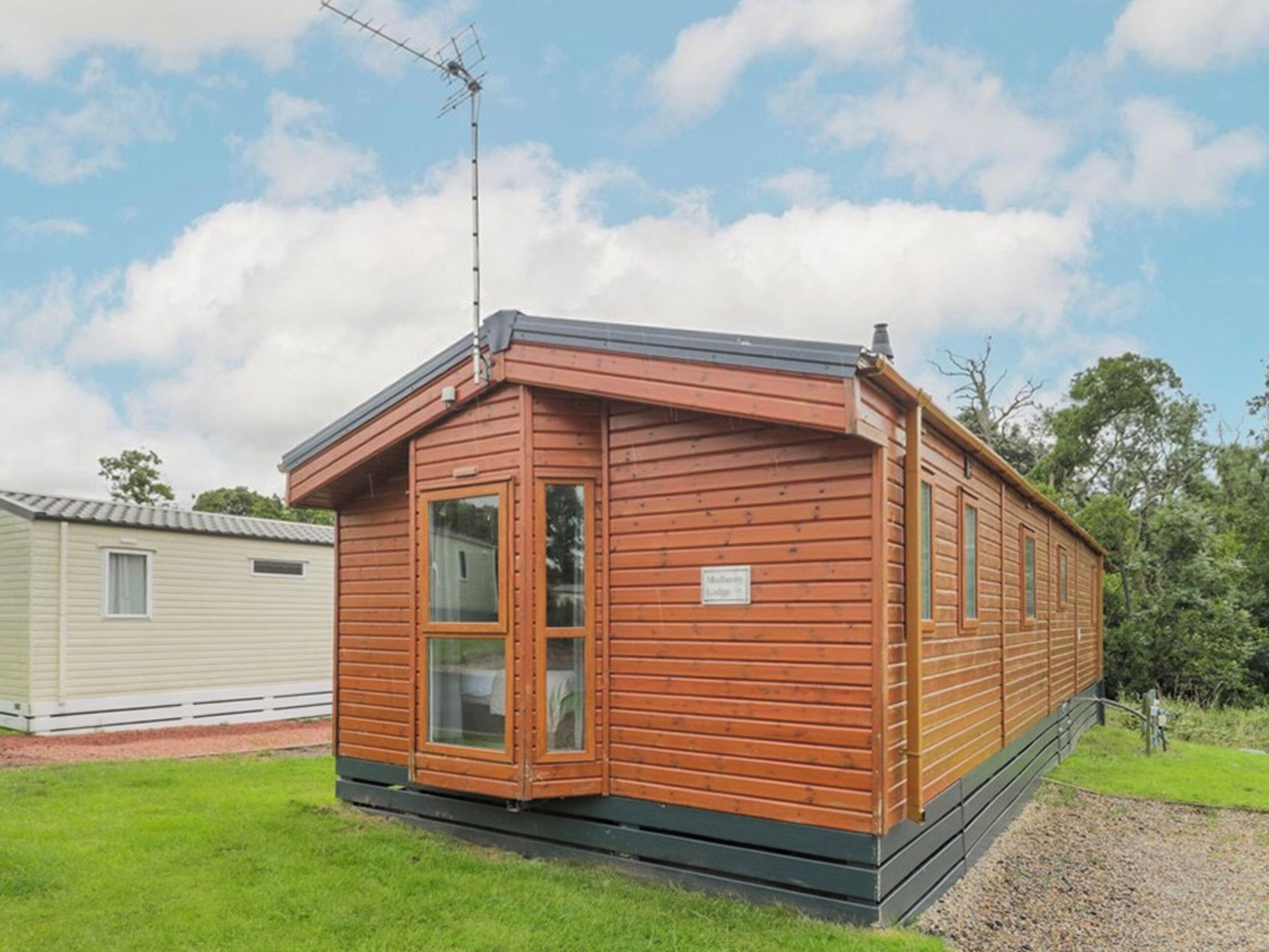 Una casa móvil de madera con techo inclinado, un pequeño porche y una antena parabólica.