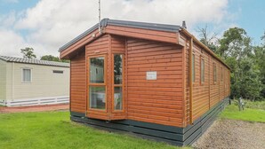 Ein Holz-Mobilheim mit Satteldach, einer kleinen Veranda und einer Satellitenschüssel.