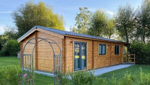 Una cabaña de madera con techo inclinado, puerta principal y una ventana pequeña.