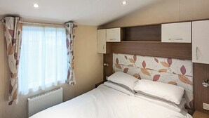 A neatly made bed with white linens in a room with a wooden headboard and a window with sheer curtains. - Riverside Retreat - UK51191 (Morpeth)