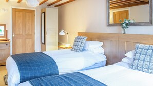 Habitación de hotel con dos camas, vigas de madera en el techo, una mesita de noche con lámpara y un espejo en la pared.