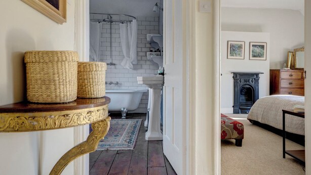 Une chambre à coucher comprenant un lit, une commode, une cheminée et une salle de bain avec une baignoire et une douche.