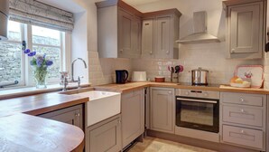 Une cuisine moderne avec des meubles gris, un four encastré et une fenêtre donnant sur l’extérieur.