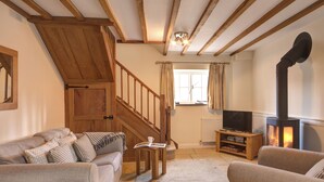 A cozy living room with a fireplace, wooden staircase, and comfortable seating. - 1 bedroom accommodation in Chipping Campden (Chipping Campden)
