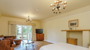 Une pièce spacieuse avec un grand lit, un canapé en cuir, une armoire en bois, une télévision et un lustre.