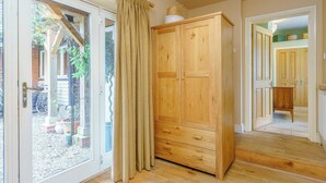 Une armoire en bois avec de nombreux tiroirs, une porte en verre avec des rideaux et un plancher en bois.