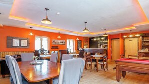 Un espace repas comprenant une table de billard, plusieurs tables et des chaises.