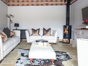 A living room with a white sofa, a coffee table, a fireplace, and a cowhide rug. - The ultimate chic space for those seeking a stylish getaway. (Chipping Campden)