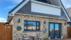 A two-story house with a stone facade, a balcony, and a front door. - Sea Breeze - UK51253 (Kimmel Bay)
