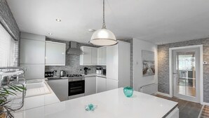 A modern kitchen with white cabinetry, a central island, and a pendant light. - Sea Breeze - UK51253 (Kimmel Bay)