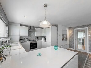 A modern kitchen with white cabinetry, a central island, and a pendant light. - Sea Breeze - UK51253 (Kimmel Bay)