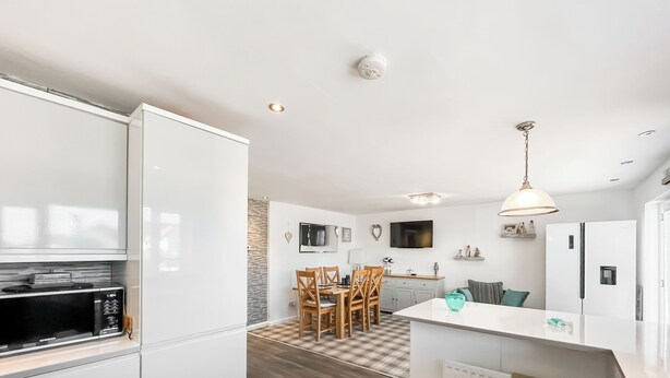 A modern kitchen with white cabinetry, a built-in microwave, and a central island with a sink. - Sea Breeze - UK51253 (Kimmel Bay)