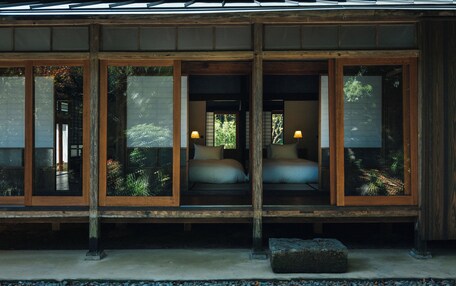 A traditional Japanese-style room with sliding doors, a bed with pillows, and a small table.