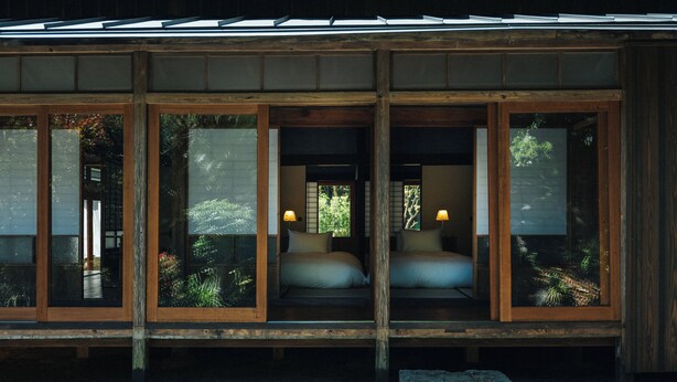 A traditional Japanese-style room with sliding doors, a bed with pillows, and a small table. - HOTEL RACCAN (Shibushi)