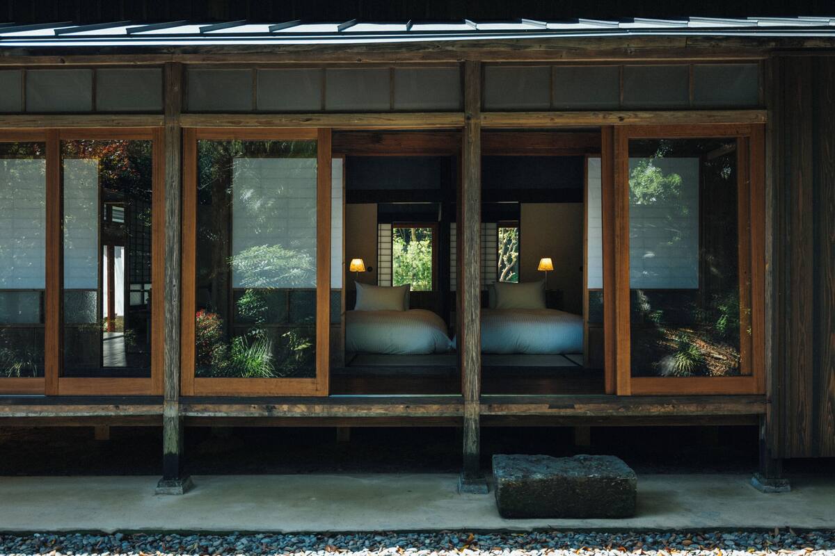 Ein traditioneller japanischer Raum mit Schiebetüren, einem Bett mit Kissen und einem kleinen Tisch.