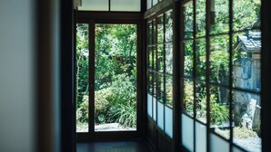 A traditional Japanese room with tatami flooring, a shoji screen door, and a view of a lush garden. - HOTEL RACCAN (Shibushi)