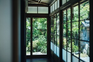 Una habitación japonesa tradicional con suelo de tatami, puerta corredera shoji y vista a un jardín exuberante.