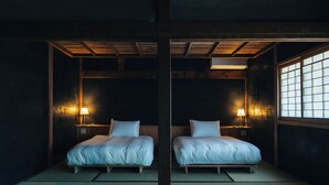A traditional Japanese room with tatami flooring, two beds with wooden frames, and sliding doors. - HOTEL RACCAN (Shibushi)