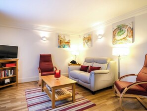 A living room with a wooden coffee table, two armchairs, a bookshelf, and a flat-screen TV. - 2 bedroom accommodation in Bath (Bath)
