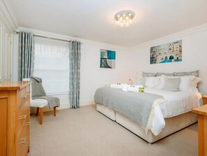 A bedroom with a bed, a chair, a dresser, a window with curtains, and artwork on the walls. - 2 bedroom accommodation in Bath (Bath)