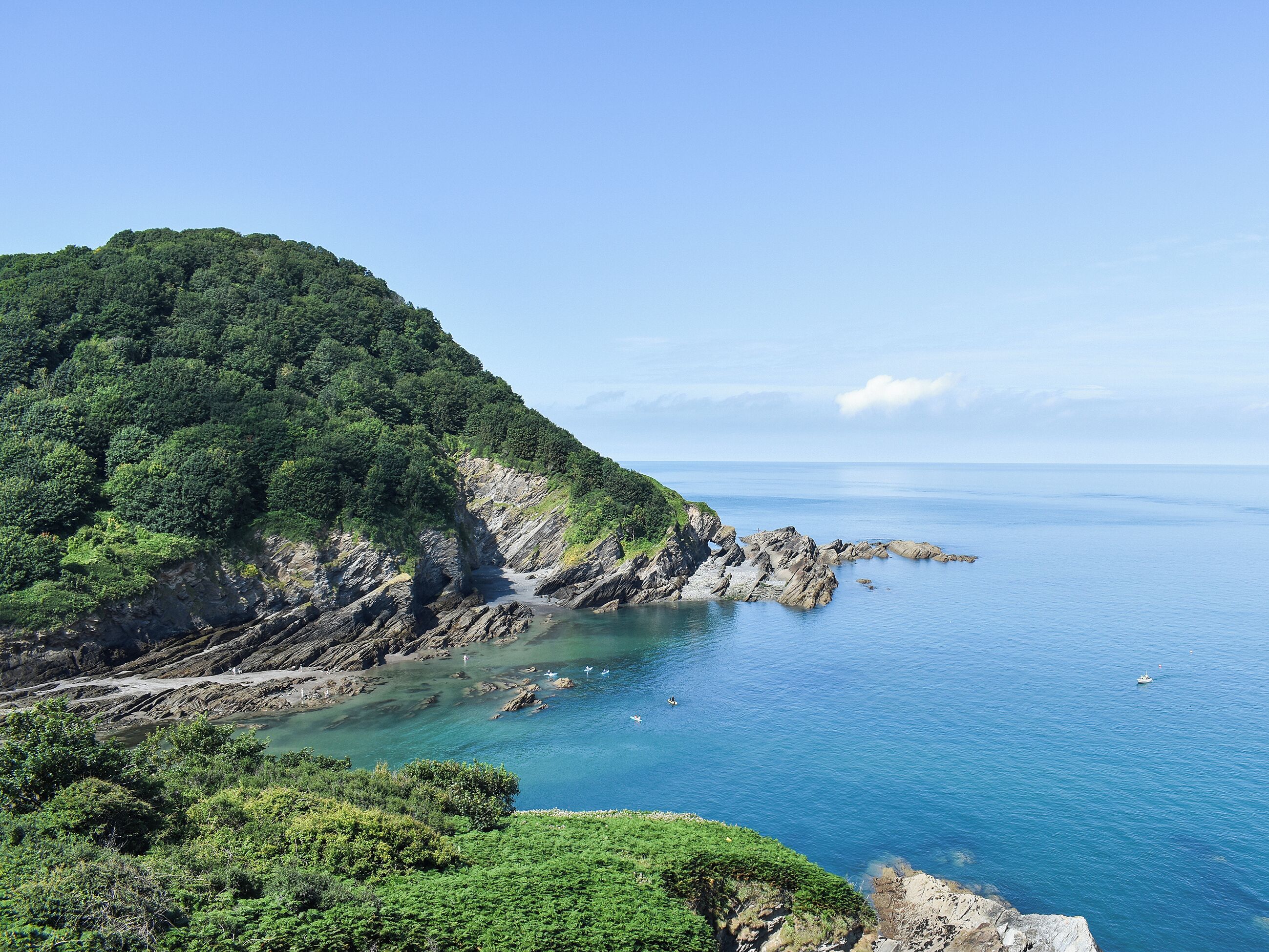 A coastal landscape with rocky cliffs and a clear view of the sea.