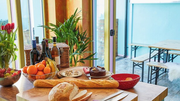 Une table en bois avec du pain, un couteau et un saladier de fruits.