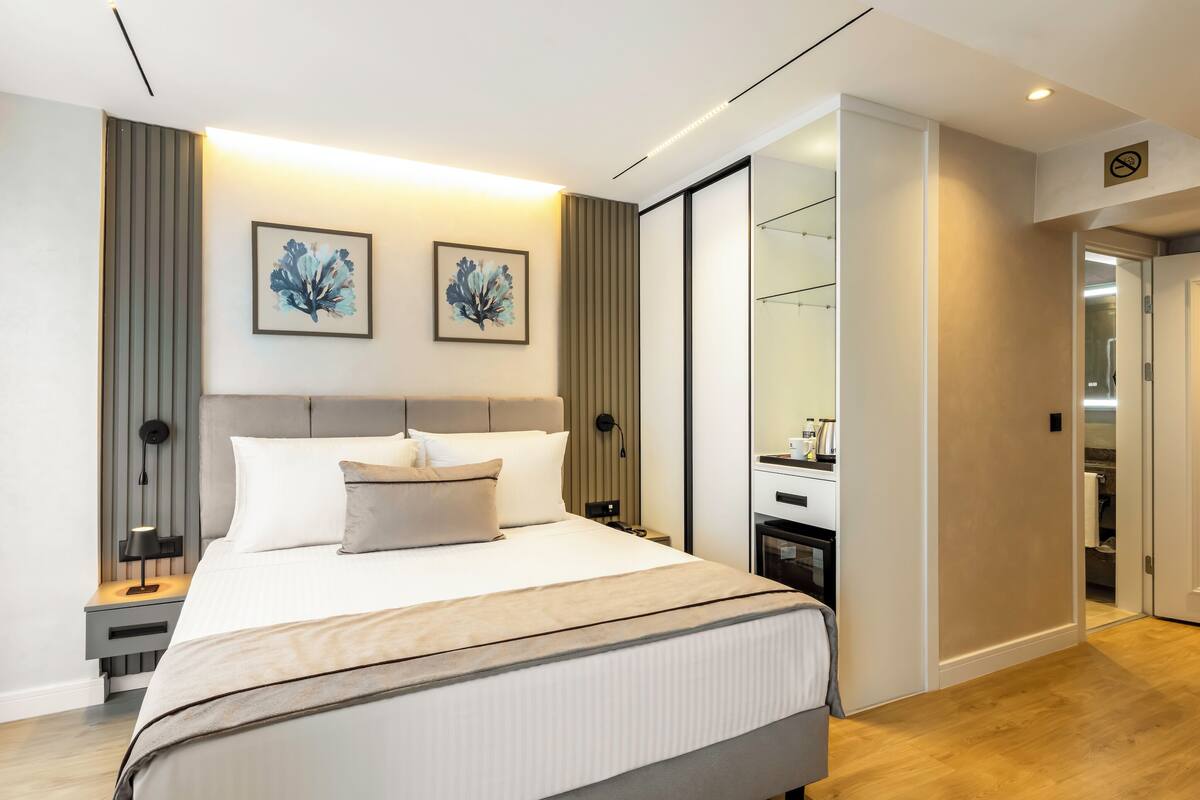 A modern bedroom with a large bed, bedside tables, and artwork on the wall.