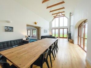 A spacious room with a long wooden table, a dark sofa, and a fireplace.