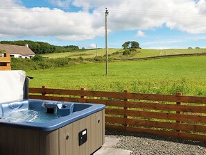 A hot tub with a wooden fence, a grassy field, and a stone wall in the background. - Jack's Hideaway - UK5530 (Gatehouse of Fleet)