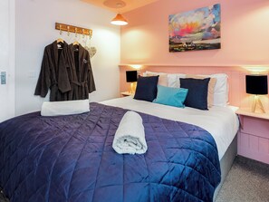 A neatly made bed with a blue quilt, a white towel, and a painting of a landscape on the wall. - Jack's Hideaway - UK5530 (Gatehouse of Fleet)