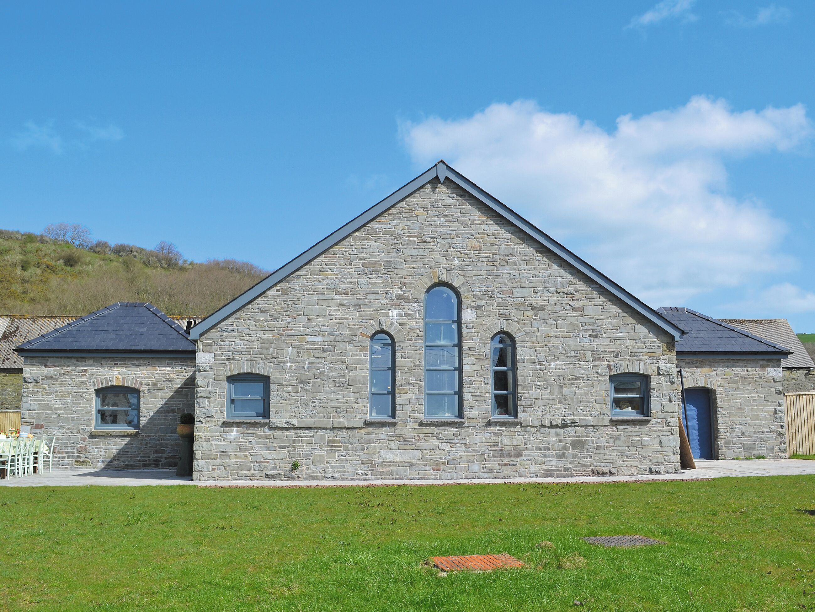 A stone building with a triangular roof and two smaller attached structures.