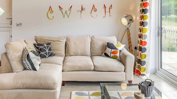A living room with a sofa, pillows, a lamp, and a wall with letters.