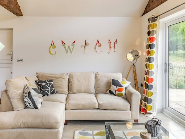 A living room with a sofa, pillows, a lamp, and a wall with letters.